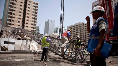 Construction workers work away to clean up remains of a crane that collapsed earlier that morning on Tuesday, July 12, 2011, during the morning rush hour in downtown Abu Dhabi. No one was hurt and only road blocks and the crane itself suffered damages. (Silvia Razgova/The National)