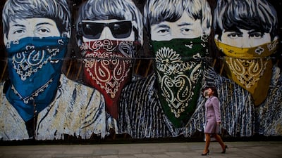 A woman walks past a mural in Central London depicting The Beatles wearing bandanas, by the Paris-born, Los Angeles-resident filmmaker and street artist Mr Brainwash, on November 8, 2012. AFP Photo