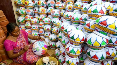 A woman paints earthenware pots ahead of the Hindu harvest festival Pongal in Chennai on January 6, 2025. (Photo by R. Satish BABU / AFP)