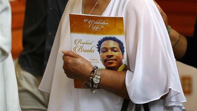 A family member carries the Celebration of Life programme for Rayshard Brooks. AP