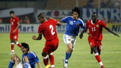 Japan's Tatsuya Tanaka, sitting left, cries out in pain as teammate Shunsuke Nakamura, Bahrain's Mohamed Hussain, centre, and Abdulla Omar, right, vie for the ball at Bahrain National Stadium in Riffa.