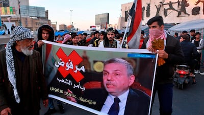 Protesters chant slogans while holding a poster of newly appointed Prime Minister Mohammed Allawi with Arabic that reads, "Rejected by the people" during a demonstration in Tahrir Square, Baghdad. AP Photo
