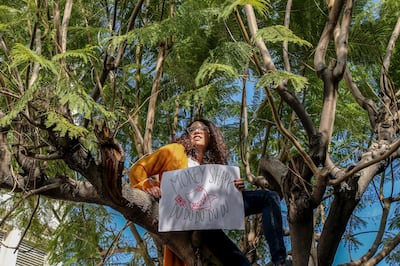A Lebanese protester sits on a tree holding a placard during an anti-government protest in front of the Lebanese Central Bank at Hamra Street in Beirut. EPA