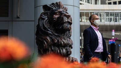 A person stands next to a statue of a lion in front of the HSBC Holdings Plc headquarters building in Hong Kong. Bloomberg