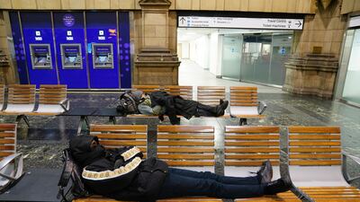 Passengers rest at Edinburgh Waverley train station as rail services to and from Scotland have been suspended. PA