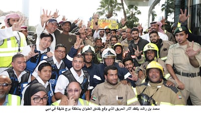 Firefighters and other people involved in the clean up pose with Sheikh Mohammed bin Rashid, Ruler of the emirate and Vice President. WAM