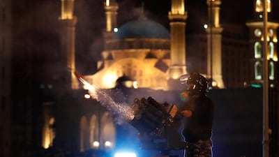 A riot police officer fires tear gas from a launcher against anti-government protesters trying to enter parliament square in downtown Beirut. AP