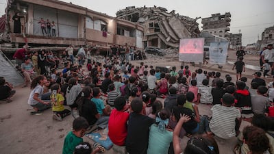 Internally displaced Palestinian children watch a film at a makeshift open-air cinema near the ruins of destroyed buildings in Gaza city. EPA