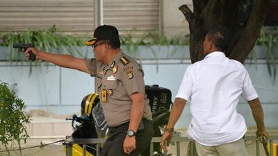 An Indonesian policeman fires his handgun towards suspects outside a cafe. Bay Ismoyo / AFP Photo