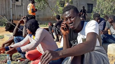 A migrant, who survived a deadly shipwreck, with other survivors on a sandy beach on the coast of al-Khums, Libya. AFP
