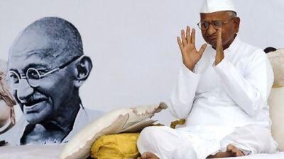 Indian activist Anna Hazare, 73, gestures during his hunger strike against corruption, besides a portrait of Mahatma Gandhi, in New Delhi