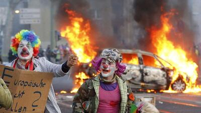 Demonstrators dressed as clowns pass by a burning police car in Frankfurt, Germany. 'Blockupy' activists tried to blockade the new headquarters of the ECB to protest against government austerity and capitalism. Michael Probst / AP Photo