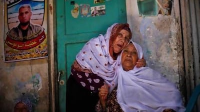 The mother (left) of Palestinian prisoner Ateya Abu Moussa (pictured in poster on the left), who has been held by Israel for 20 years, hugs her sister after hearing news on her son’s expected release.