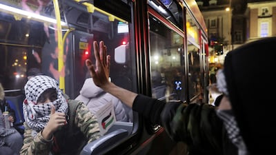 A bus passenger wearing a keffiyeh gestures to a protester also wearing one on Staten Island, New York, on November 14, 2023. Reuters