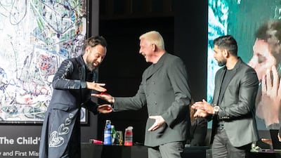 Tennis player Boris Becker, boxer Amir Khan and Marjorie Harvey place a finishing hand print on one of Sacha Jafri's art works during an art auction to raise money for the 100 Million Meals campaign in Dubai. Antonie Robertson / The National