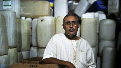 Ali, a smuggler and middleman stands in front of a stock of gasoline containers in the bottom floor of his house in Kasserine, Tunisia.
