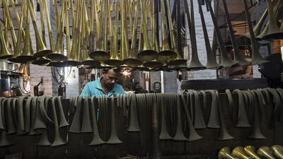 Bell components from various types of brass instruments hang from a rail and the back board of a work bench in the sand-filing department of the Nadir Ali & Co factory, in Meerut, Uttar Pradesh, India, Prashanth Vishwanathan / Bloomberg