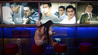 A woman looks at her mobile phone at the entrance of a cinema in Beijing. Wang Zhao / AFP