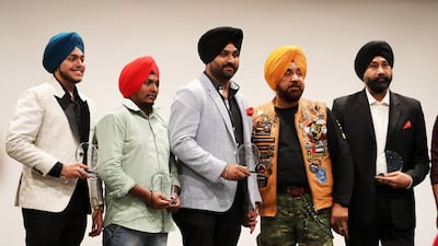 Gurnam Singh, founder of Singhs Motorcycle Club UAE, second from right, honouring Amandeep Singh, founder of Bhangra Crew Dubai, centre, and other members of the school.