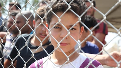 A young Syrian refugee looks through a fence from inside the Pournara refugee camp in Cyprus on June 23, 2020. EPA