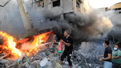 A Palestinian man uses a fire extinguisher to douse a fire following an Israeli strike, in Khan Yunis in the southern Gaza Strip. AFP