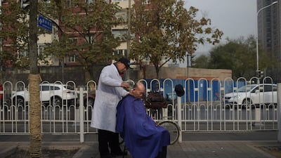 A man gets a haircut on a street in Beijing. Nicolas Asfouri / AFP Photo