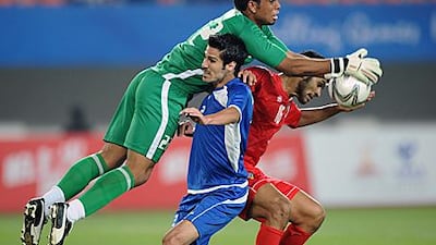 UAE’s Ahmed Mahmoud Juma, in green, catches the ball as his teammate Saeed Salem al Kathiri, in red, vies with Abdullah Abdullah, of Kuwait, in the Asian Games last-16 game in Guangzhou.