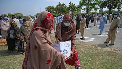 Women in need carry foodstuff being distributed by the UAE embassy in Islamabad.