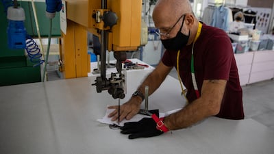 A technician cuts out stencils for silk gloves.