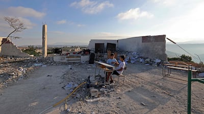 Students sit on a desk lying outside the Borj Qalaouiyé Intermediate School, whose campus was earlier damaged by Israeli strikes. AFP