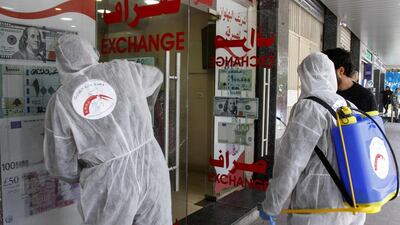 Volunteers with Lebanon's Disaster Management Unit disinfect a currency exchange in the southern city of Saida on March 12, 2020 to prevent the spread of coronavirus. AFP