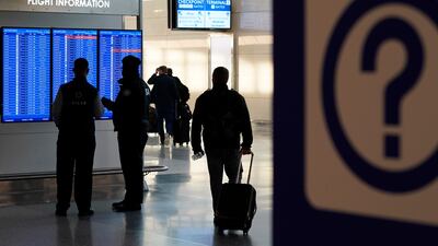 People look at a video display showing flight delays and cancellations at Ronald Reagan Airport. AP