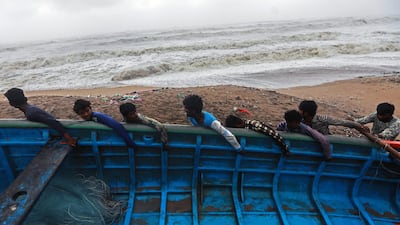 Indian fishermen move a fishing boat to a safer place along the Arabian sea coast, as Cyclone Vayu approaches Veraval, India. EPA