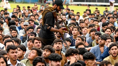 An Afghan security guard walks past fans watching a live broadcast at the Kabul International cricket stadium. AFP