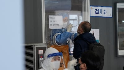 Medical workers take nasal samples from people at a makeshift coronavirus testing site in Seoul, South Korea. AP