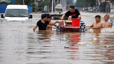 People with a makeshift raft look for others to rescue in Zhengzhou, where the floodwater is chest-high in some areas.