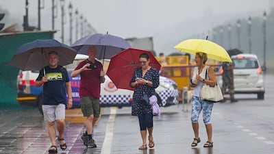 Visitors use umbrellas as walk on Kartavya Path, formerly known as Rajpath, as they visit newly inaugurated central vista project near India Gate during a rainfall in New Delhi in September 23, 2022. (Photo by Money SHARMA / AFP)