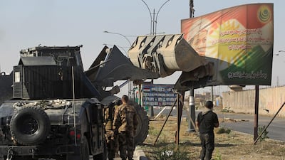 Iraqi forces use a tractor to damage a poster of Iraqi Kurdish president Massud Barzani on the southern outskirts of Kirkuk.