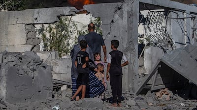 A Palestinian family stands next to their destroyed home after an Israeli air strike in southern Gaza city, in which more than 14 people were injured. EPA