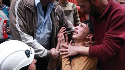A man is comforted by a rescue worker and others following a reported air strike by government forces in which a fellow rescue worker was killed on March 9 in the northern city of Aleppo. Baraa Al Halabi/AFP Photo
