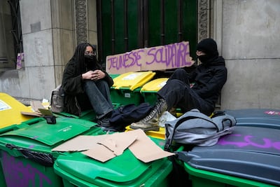 Striking pupils sit on rubbish bins outside their high school on Tuesday. AP