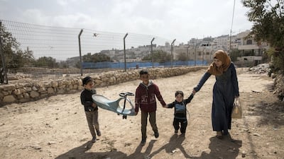A Palestinian woman with children pass by the fence of the new archeological park that the Israeli government and army Palestinian neighbourhood of Tel Rumeida in Hebron .