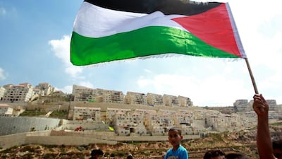 A protester waves a Palestinian flag in front of the Israeli West Bank settlement of Beitar Illit on September 5, 2014, during a demonstration against Israel’s decision to expropriate 400 hectares of land in the territory. Musa Al Shaer / AFP