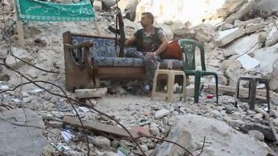 A Free Syrian Army fighter sits on a sofa along a street in Aleppo's Salaheddine neighbourhood. Nearby Khan Al Assal, the scene of a purported chemical attack, had been taken by the rebels last week.