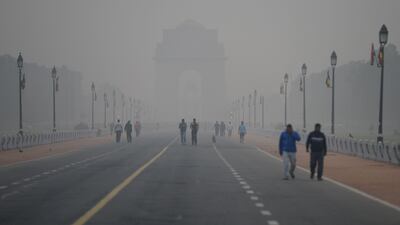 People walk early in the morning as smog covers India Gate war memorial in New Delhi on November 6, 2017. Delhi, one of the world's most polluted cities, suffers from high levels of pollution during winter months, with millions of vehicles contributing to the city's bad air. / AFP PHOTO / SAJJAD HUSSAIN