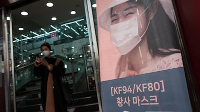 A South Korean woman, left, wearing a mask exits a store in central Seoul. EPA