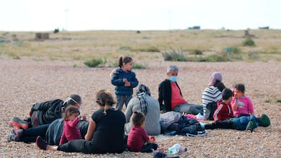 A group of migrants rest on the beach as they wait for UK Border Force officials at Dungeness, southern England. AP