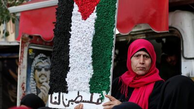 A Palestinian woman holds a Palestine flag with Arabic words that read: "Palestine for us," as she attends a protest against the White House plan for ending the Israeli-Palestinian conflict at Burj al-Barajneh refugee camp, south of Beirut, Lebanon. AP