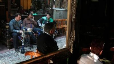 Egyptians and tourists smoke shisha and drink tea in the popular El-Fishawi coffee shop in the tourist bazaar close to the Al-Hussein mosque in Cairo on March 15, 2011.