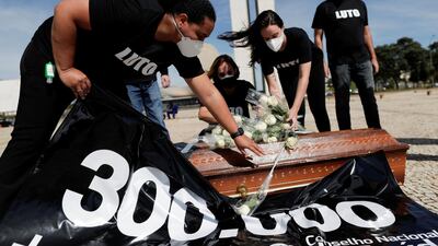 Healthcare workers in Brazilia place flowers representing dead colleagues on top of a coffin during a protest against President Jair Bolsonaro and his coronavirus policies. Reuters